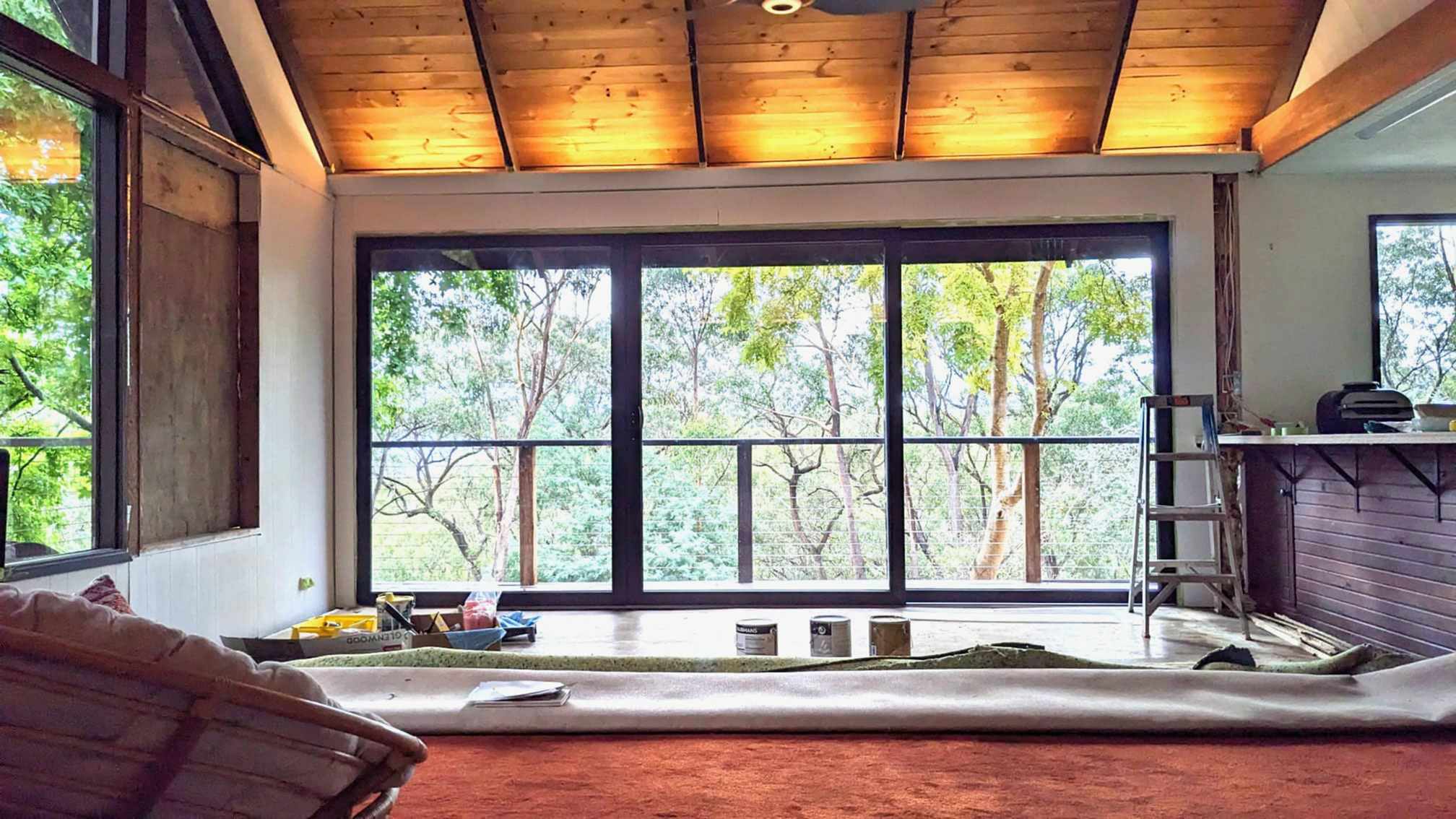 Black-brown sliding stacker door in the living room of a house with a forest view